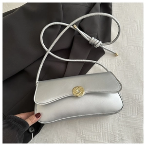 Detail of silver shoulder bag featuring a golden knot-shaped twist lock and premium PU leather