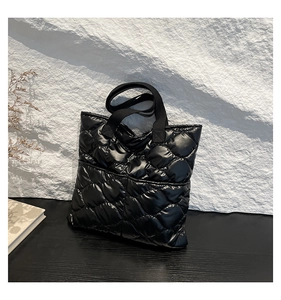 Close-up of black quilted tote bag showing premium glossy finish and diamond stitching