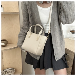Detail of a beige mini bucket bag with gold hardware and a detachable shoulder strap