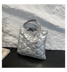 Detail of silver metallic quilted tote bag with heart patterns on stone background