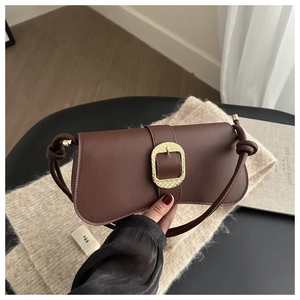 Detalle del bolso de cuero café con hebilla dorada y correa con nudos decorativos