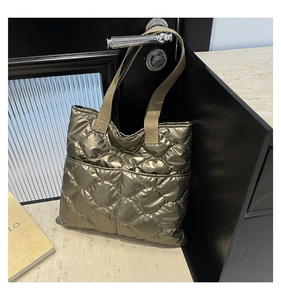 Detail of metallic gold quilted tote bag with large diamond stitching on black door handle