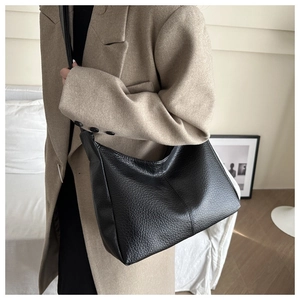 Close-up of black lychee grain leather hobo bag worn by model in minimalist setting