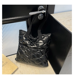 Detail of black quilted puffer tote bag with glossy finish hanging on a handle