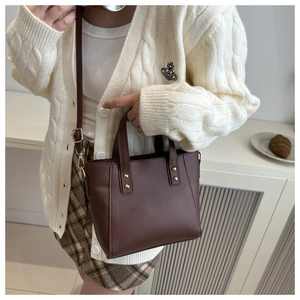 Detail view of brown faux leather tote bag with gold metal studs and detachable strap