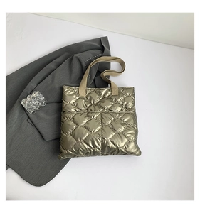 Detail of metallic olive green quilted tote bag with texture on a grey blazer
