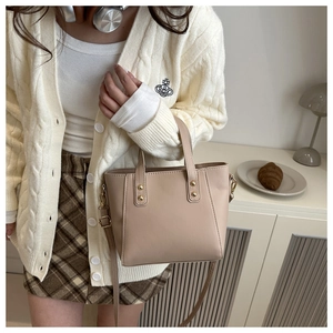 Close-up of beige vintage tote bag with gold rivets and detachable shoulder strap