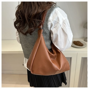 Brown large capacity leather hobo bag worn by model in a minimalist setting