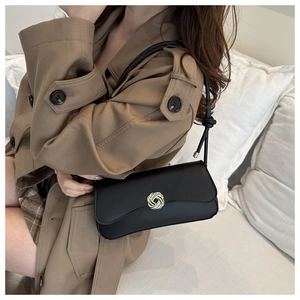 Detail of black rectangular underarm bag featuring a silver woven knot buckle and slim strap