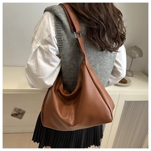 Brown litchi grain leather hobo bag worn by model showing its large capacity and drape