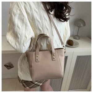 Detailed view of beige faux leather tote with golden rivets and detachable shoulder strap