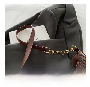 Détail du sac sous le bras à motif léopard avec chaîne dorée et bride en cuir brun