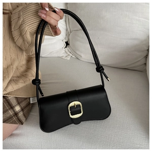 Detalle de bolso de hombro en cuero negro con hebilla dorada y correa con nudo