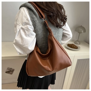 Side view of a large brown hobo bag with pebble leather texture worn on the shoulder