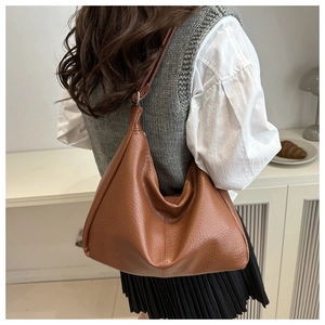 Brown leather hobo shoulder bag with litchi texture shown in a modern lifestyle outfit