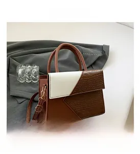 Detail of brown and white crossbody bag with crocodile texture and gold hardware