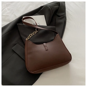 Detail of dark brown faux leather hobo bag with a chunky gold chain strap on a blazer