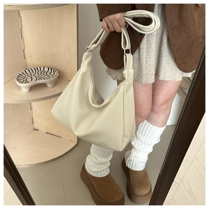 Detail of off-white lychee grain leather tote bag worn as a stylish crossbody bag