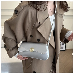 Detail of grey crossbody bag with gold woven buckle on khaki trench coat model