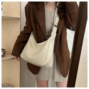 Close-up of cream leather shoulder bag with lychee texture and adjustable wide strap