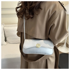 Detail of light blue leather bag with gold braided clasp on a trench coat