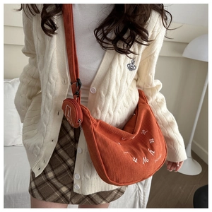 Detail of orange corduroy crescent tote bag with mini round coin purse and embroidery