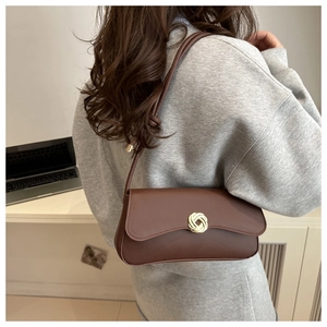Detail of dark brown leather shoulder bag with gold textured round buckle and strap