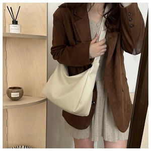 Beige pebbled leather crescent crossbody bag shown on a model for daily commute style