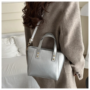 Side view of a silver metallic tote bag with gold rivets worn on a wool coat