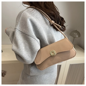 Detail of beige leather underarm bag featuring a gold spiral twist lock and knotted strap