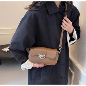 Détail d'un sac bandoulière en cuir marron avec boucle triangulaire argentée et fine