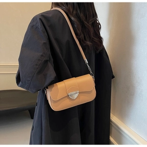 Détail d'un sac à main en cuir camel avec boucle triangle argentée et chaîne métallique