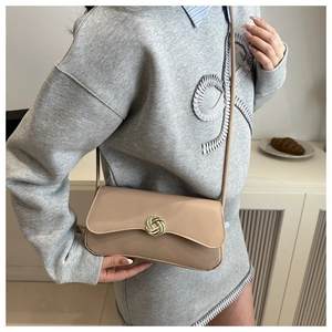 Chic beige leather shoulder bag with elegant gold twist lock shown on grey knit dress