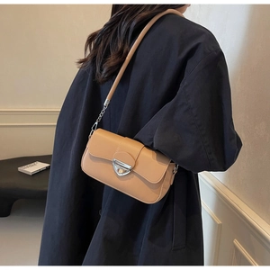 Détail du sac sous le bras en cuir marron clair avec boucle argentée porté par un mannequin