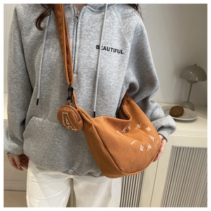 Détail d'un sac demi-lune en velours côtelé marron avec une petite pochette à monnaie