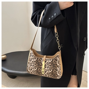 Detail of leopard print underarm bag with metal chain and camel leather strap shown on model