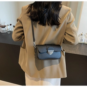 Détail d'un sac bandoulière noir minimaliste en cuir avec boucle argentée sur modèle