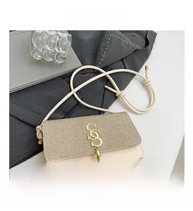 Détail du sac en cuir beige avec rabat pailleté, logo S doré et gland décoratif