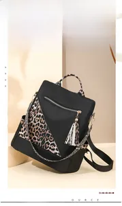 Detail of waterproof nylon backpack featuring leopard print straps and gold metal buckles