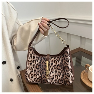 Detail of leopard print faux fur bag with gold buckle and chain strap on a wooden table