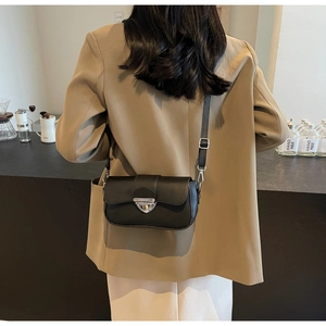 Détail d'un petit sac bandoulière noir en cuir avec fermoir triangle en métal argenté