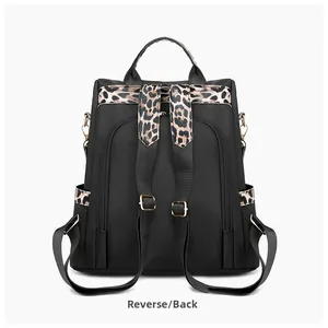 Detail view of black nylon backpack with leopard print straps and gold metal hardware