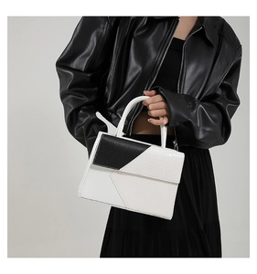 Detail of minimalist crocodile pattern handbag with black and white geometric contrast design