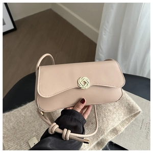 Detail of elegant beige crossbody bag showing the golden woven circular metal buckle closure