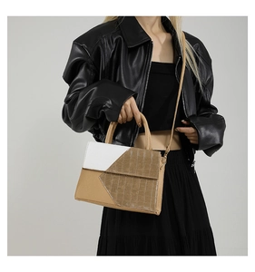 Modern mixed color handbag with crocodile pattern shown with a black leather jacket