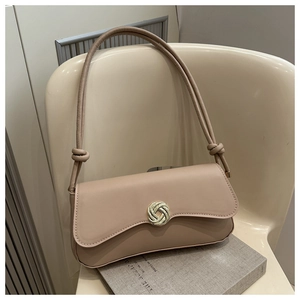 Detail of silver circular woven buckle and knotted shoulder strap on beige leather bag