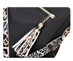 Close-up of black nylon bag with golden zippers, leopard strap, and stylish leather tassels