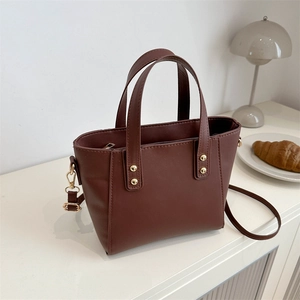 Vintage dark brown tote bag with gold rivets and shoulder strap on a table
