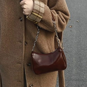 Detail of dark brown glossy patent leather shoulder bag with silver chain strap
