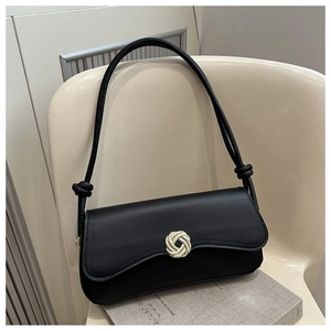Detail of black leather underarm bag with circular metal buckle and knotted shoulder strap